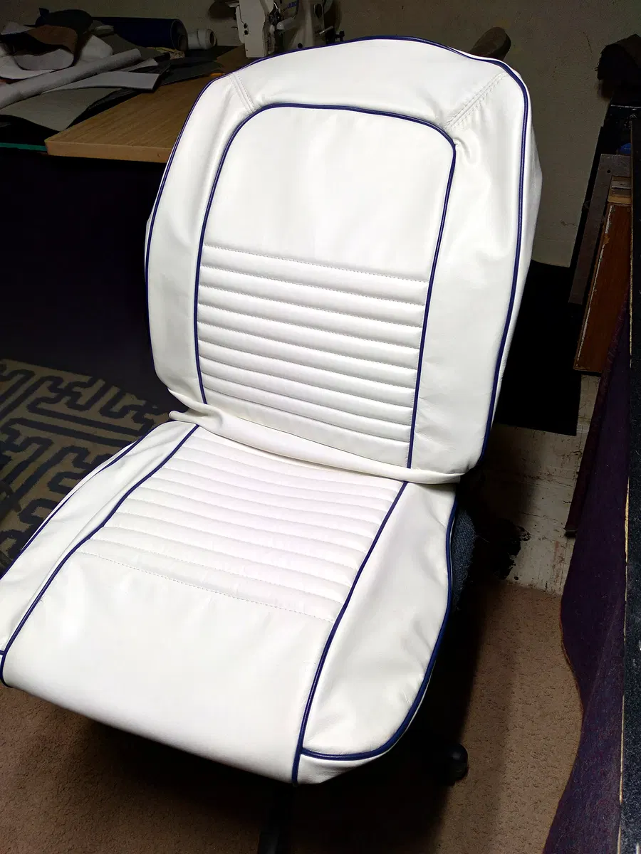 White classic Camaro-style upholstered bucket seat with contrasting dark piping and vertical stitching