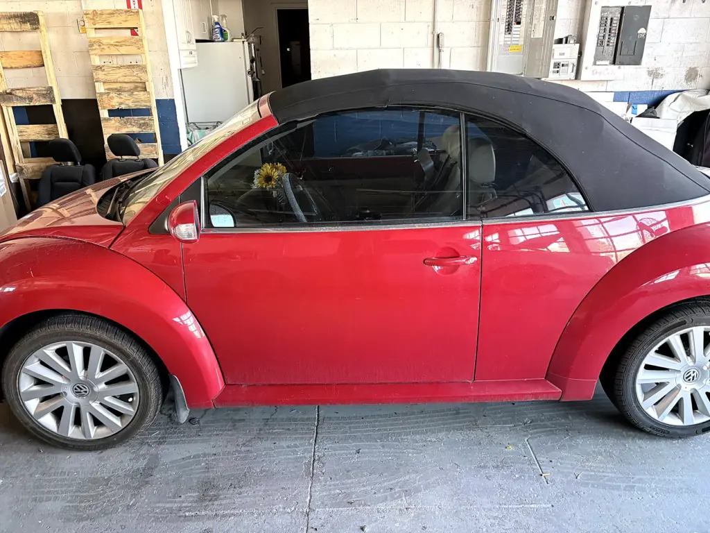 Red Volkswagen Beetle convertible with a black soft top