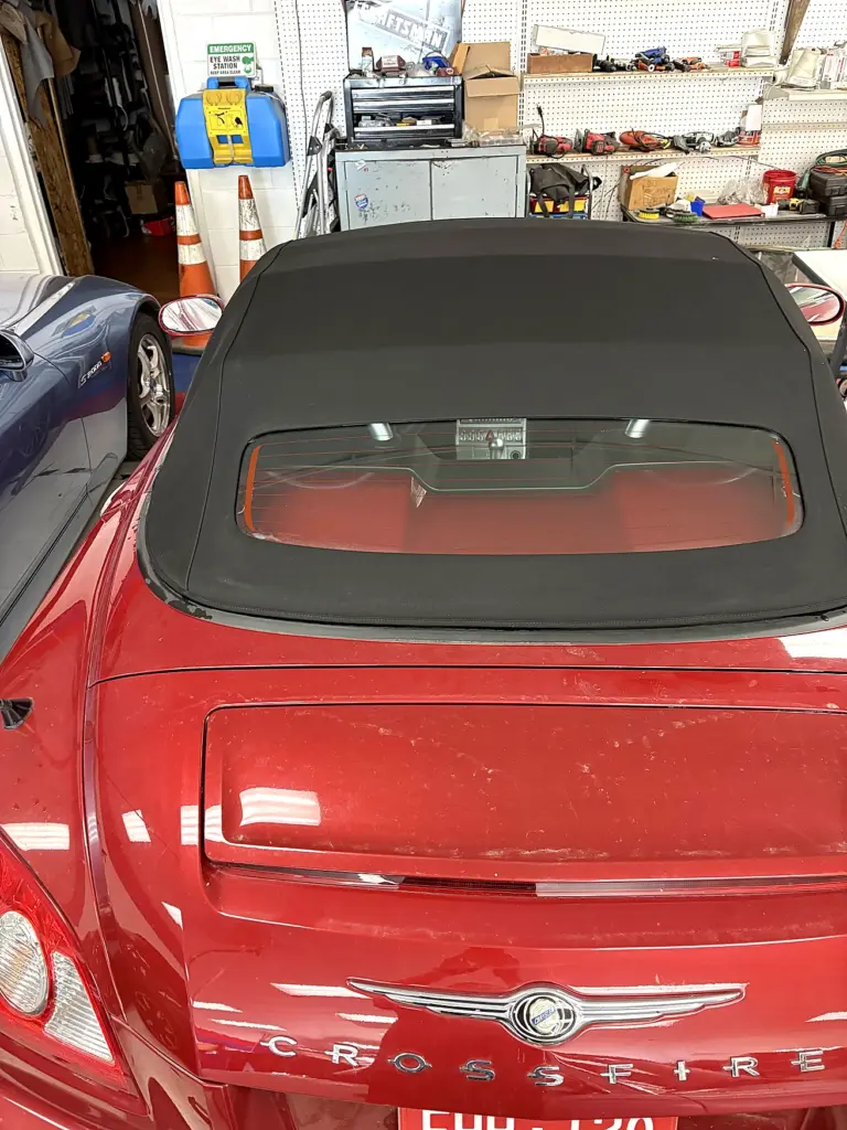 Red Chrysler Crossfire convertible at an automotive upholstery workshop