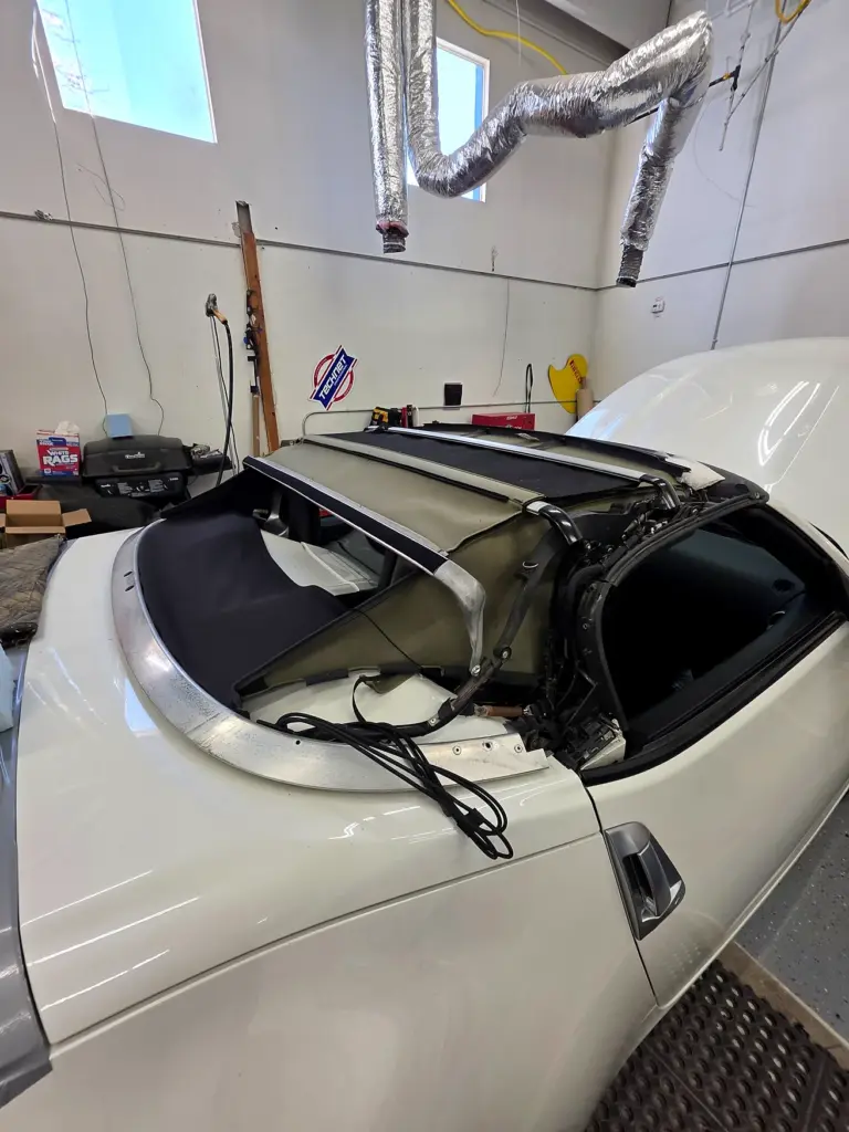 Nissan 370Z Roadster folding convertible roof assembly inside an automotive workshop