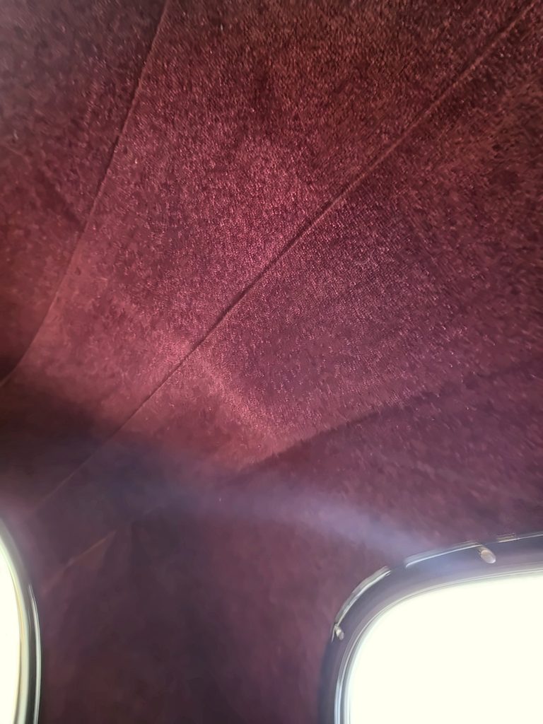 Burgundy automotive headliner upholstery showing roof lining and finished interior trim, first project angle