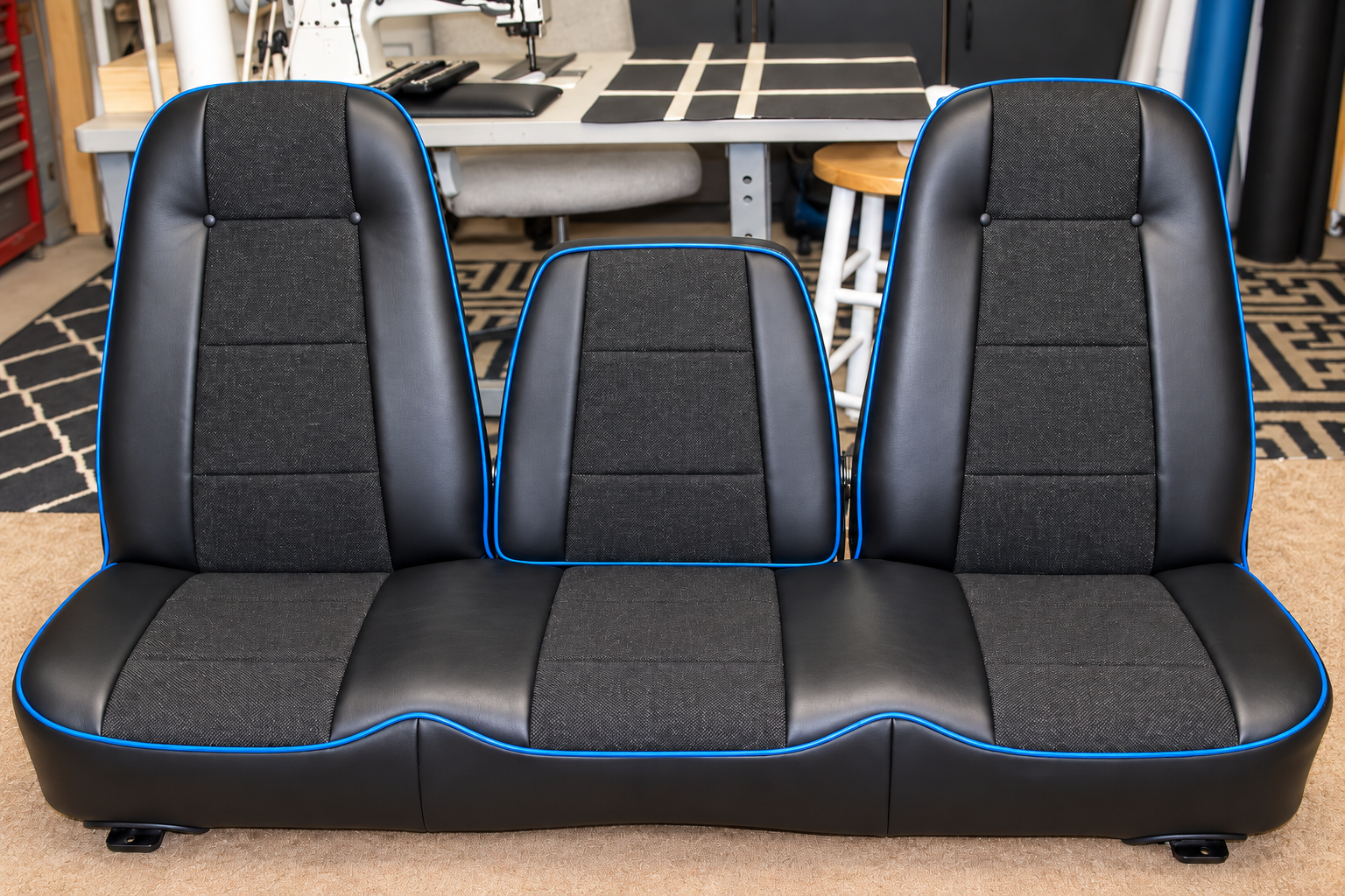 Finished custom classic bench seat with black vinyl bolsters, charcoal fabric inserts and vivid blue piping around the backrests and seat cushions