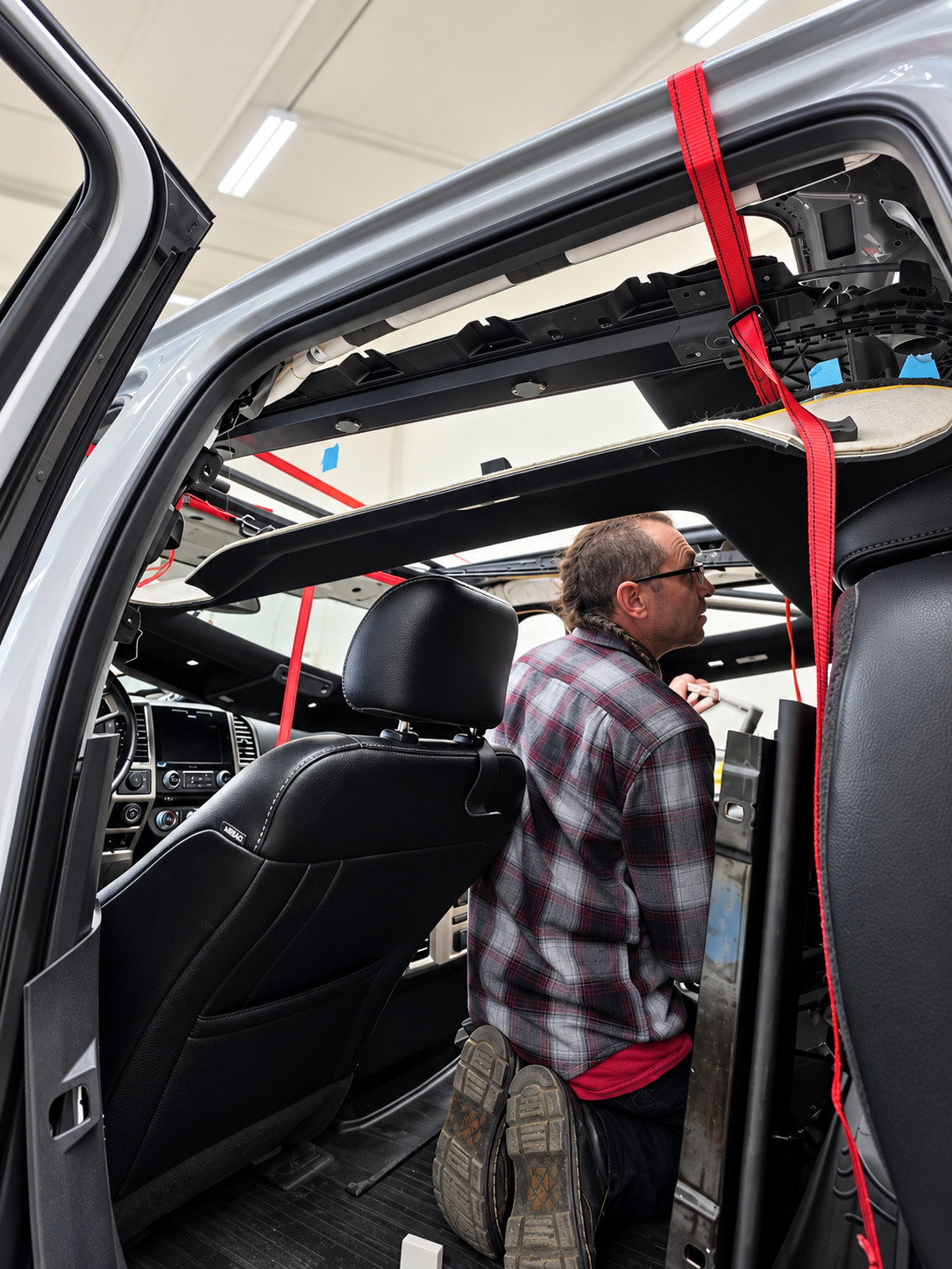 Technician working on removed SUV headliner and interior roof trim at Fine Line Auto Trim and Upholstery