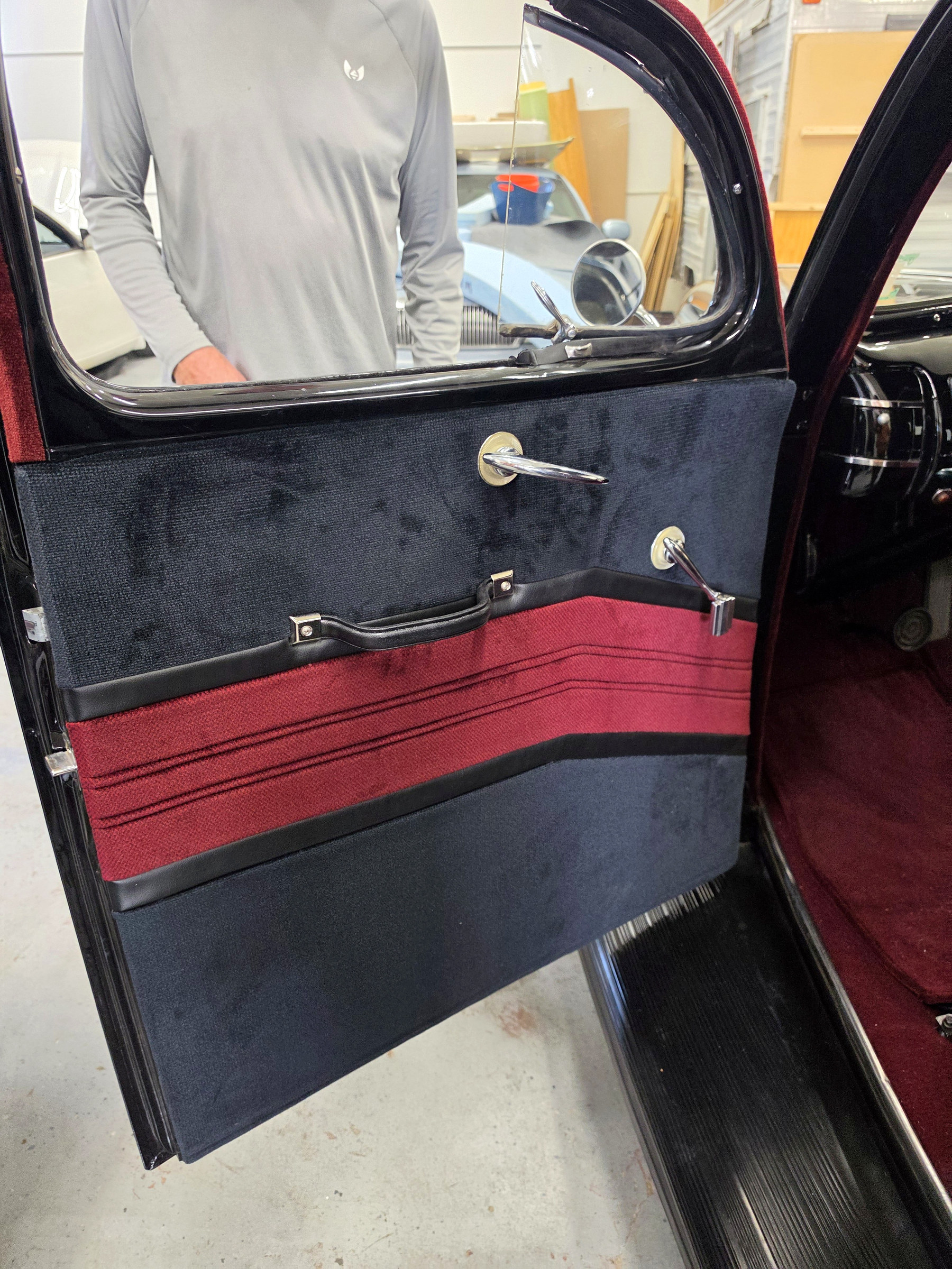 Classic car door panel with custom red and dark upholstery and restored trim