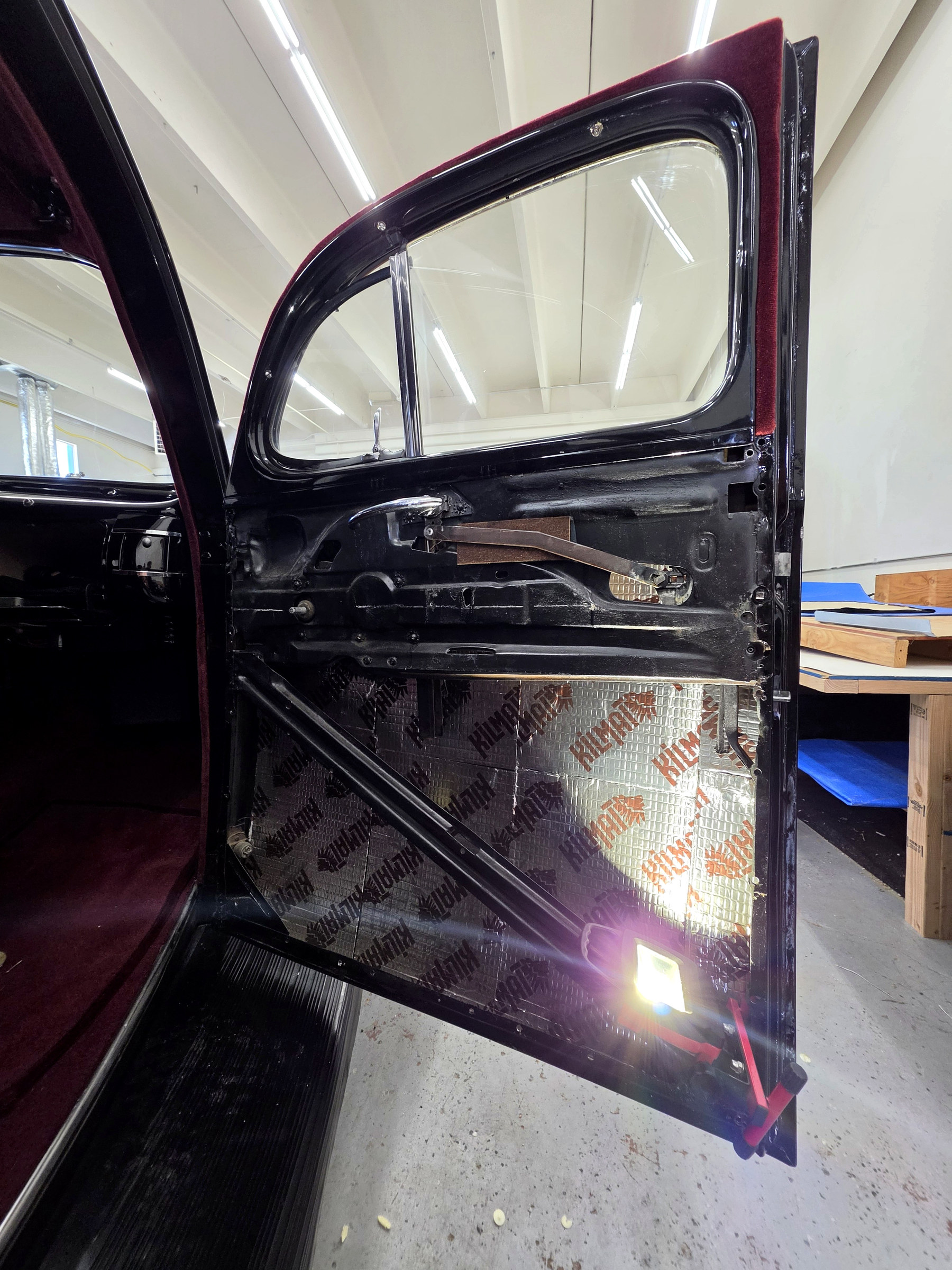 Classic car door trim in progress showing sound-deadening insulation, padding area and uncovered inner door