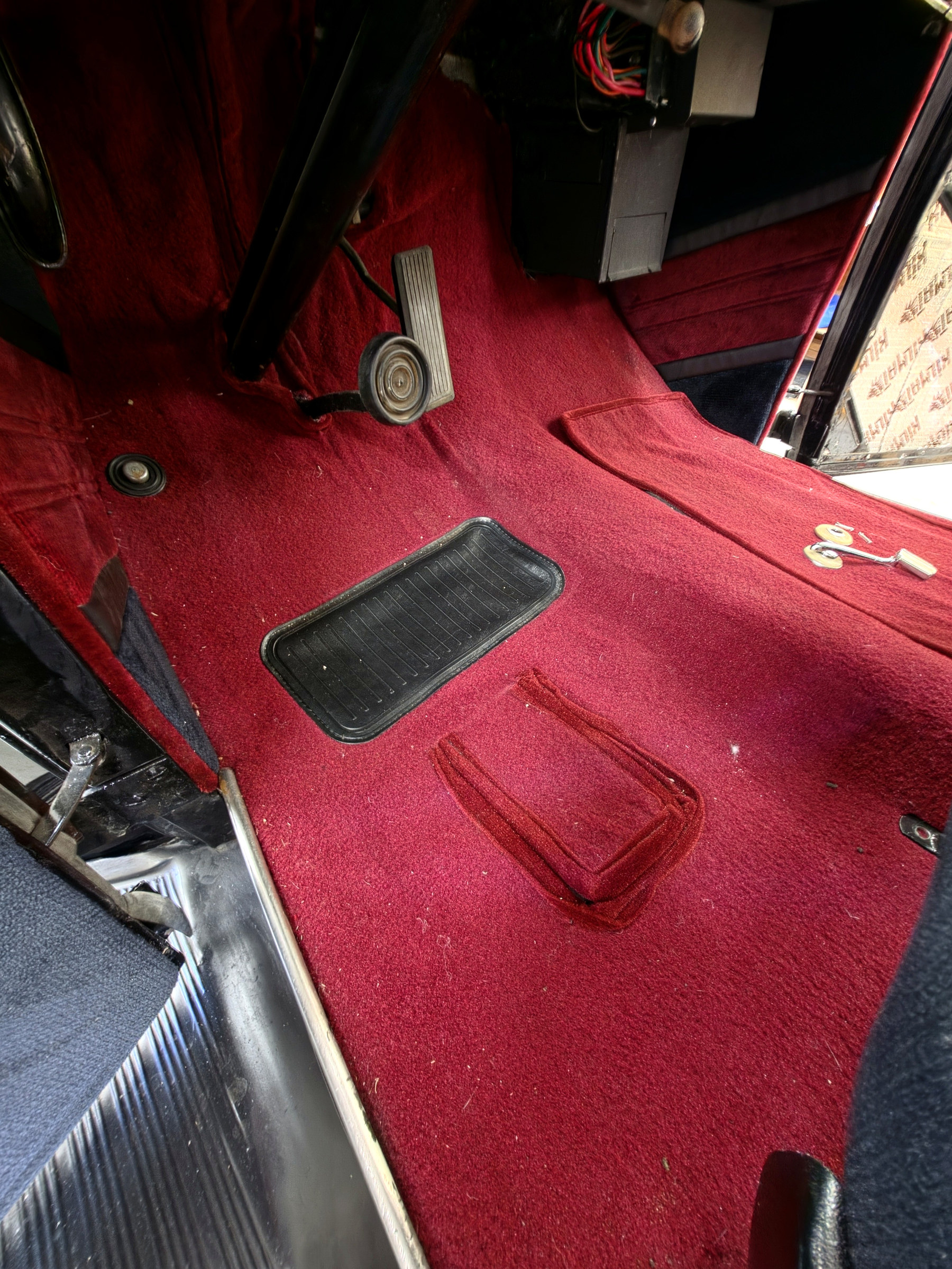 Red custom automotive floor carpeting and interior reupholstery fitted around classic car pedals and footwell